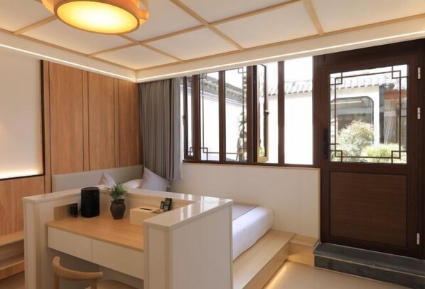 Una habitación de hotel moderna con un escritorio de madera, un sofá y un ventanal con vistas al exterior.