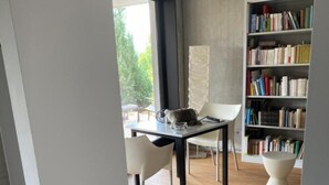 Una sala moderna con comedor, estantería y vistas al exterior.