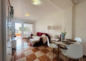 Una habitación con cama, una mesa de comedor con sillas, una lámpara y vistas al exterior.
