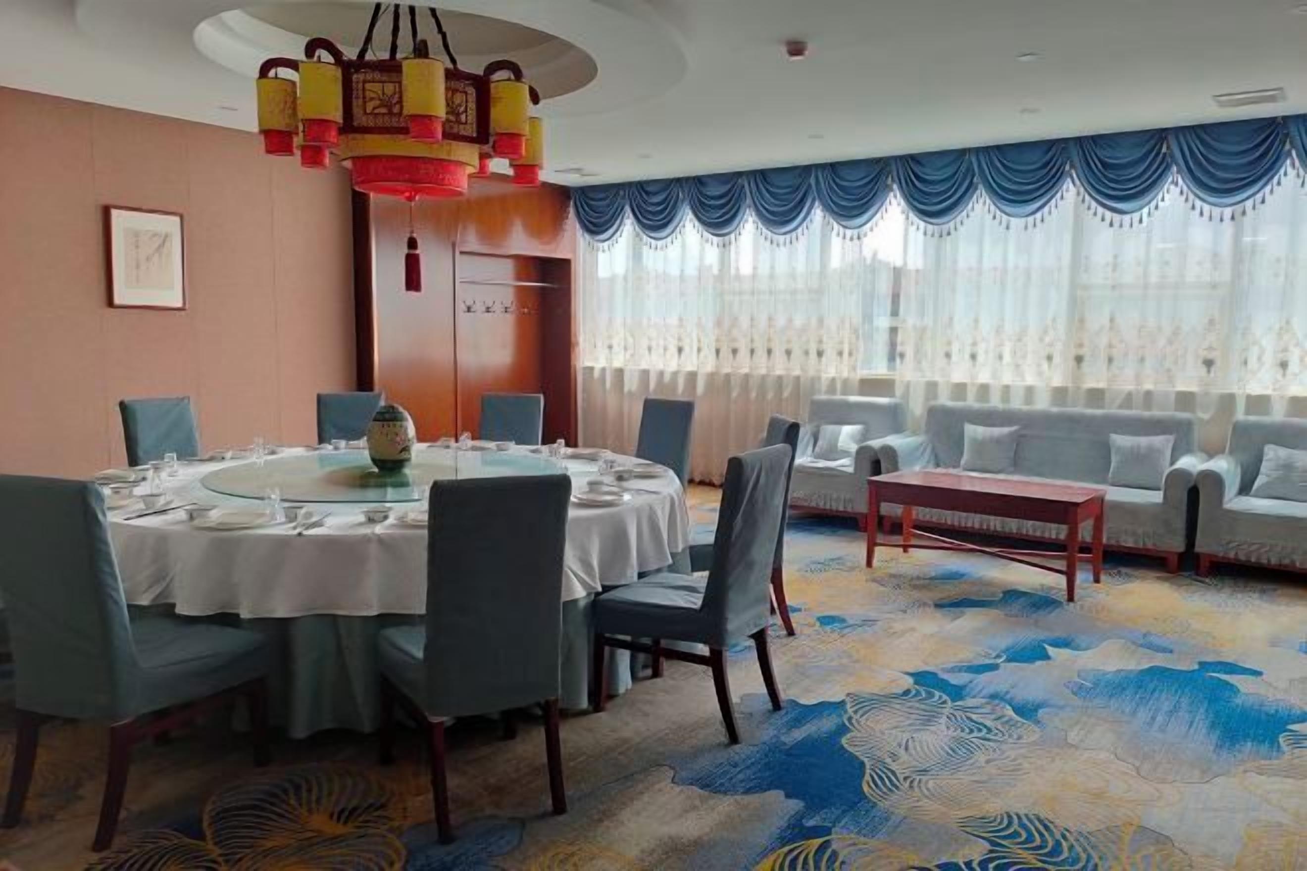 A dining area with a round table, chairs, and a decorative chandelier.