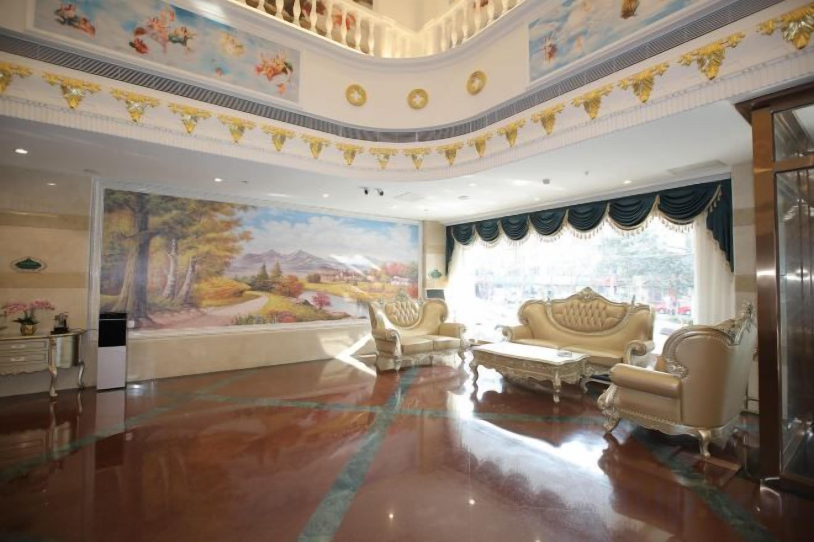 A spacious lobby with a large mural, a grand staircase, and elegant seating arrangements.