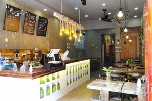 A restaurant interior with a counter, seating area, and hanging light fixtures. - Shengjin Hotel (Yangshuo)