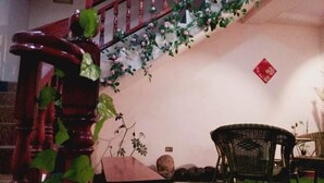 A staircase with a red railing, a wooden chair, and a small table. - Shengjin Hotel (Yangshuo)