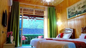 A wooden room with two beds, a chandelier, a painting, and a view through a window. - Shengjin Hotel (Yangshuo)