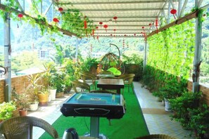 A covered outdoor area with a pool table, wicker furniture, and potted plants. - Shengjin Hotel (Yangshuo)