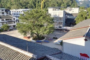 A traditional building with a tiled roof, a courtyard with a tree, and a clear view of the surrounding area. - Shengjin Hotel (Yangshuo)