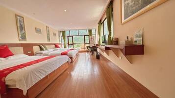 A hotel room with two beds, a wooden floor, and large windows.