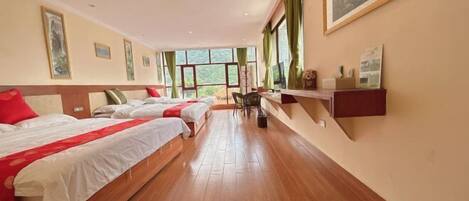 A hotel room with two beds, a wooden floor, and large windows.