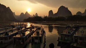 A riverfront with several boats docked, surrounded by mountainous terrain. - Shengjin Hotel (Yangshuo)