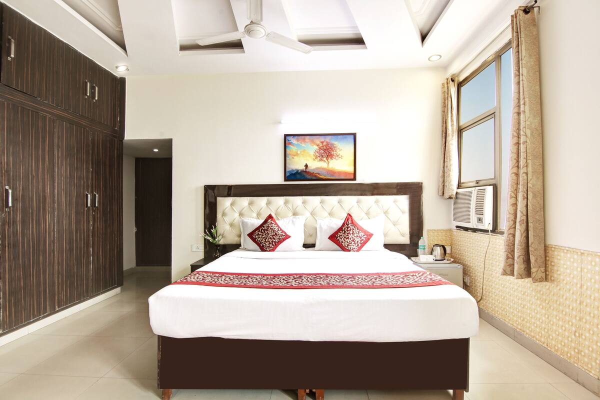 A bedroom with a large bed, a nightstand, a wardrobe, and a painting on the wall.