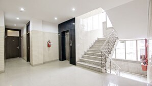 A modern hotel lobby with a staircase, a fire extinguisher, and a door. - Hotel Vibe Blue (Noida)