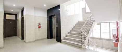 A modern hotel lobby with a staircase, a fire extinguisher, and a door.