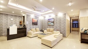 A modern living room with a reception desk, two sofas, a coffee table, and artwork on the walls. - Hotel Vibe Blue (Noida)