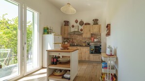 A modern kitchen with wooden cabinets, a large window, and a dining area with a wooden table. - Villa Ortensia (Mazzaforno)
