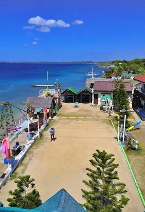 A beachside view with a sandy area, a small building, and a clear blue sky.