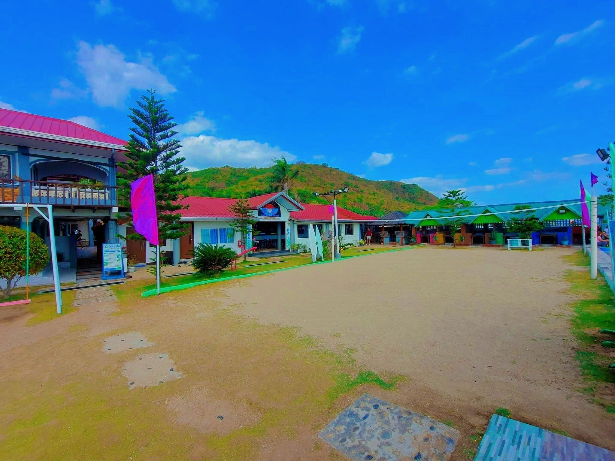 Un hotel con varias edificaciones, un amplio patio abierto y un telón de fondo montañoso.