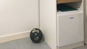 A compact, white storage unit with shelves and hanging space, a small refrigerator, and a 2kg weight on the floor. - Juste une Chambre Chez L'habitant (Saint-Sébastien-sur-Loire)