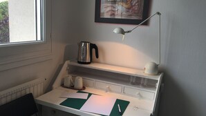 A small workspace with a desk, a kettle, a lamp, and a framed picture on the wall. - Juste une Chambre Chez L'habitant (Saint-Sébastien-sur-Loire)