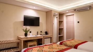 Une chambre d’hôtel comprenant un lit, un bureau avec un téléviseur à écran plat, une armoire et un petit coin salon.