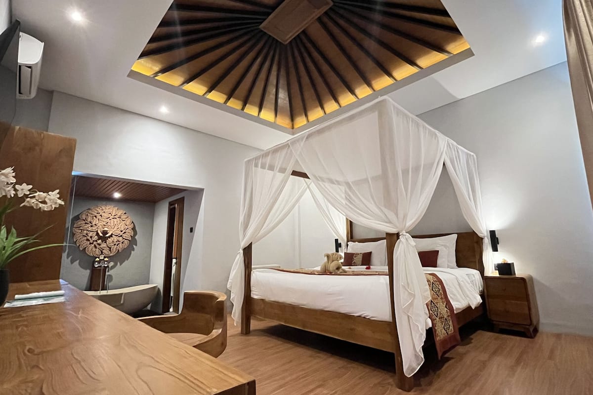 Un dormitorio moderno con cama dosel, muebles de madera y una lámpara decorativa en el techo.