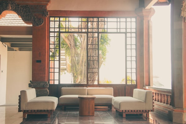 Una habitación con un conjunto de sofá, una mesa de centro de madera y un ventanal con vistas a árboles.