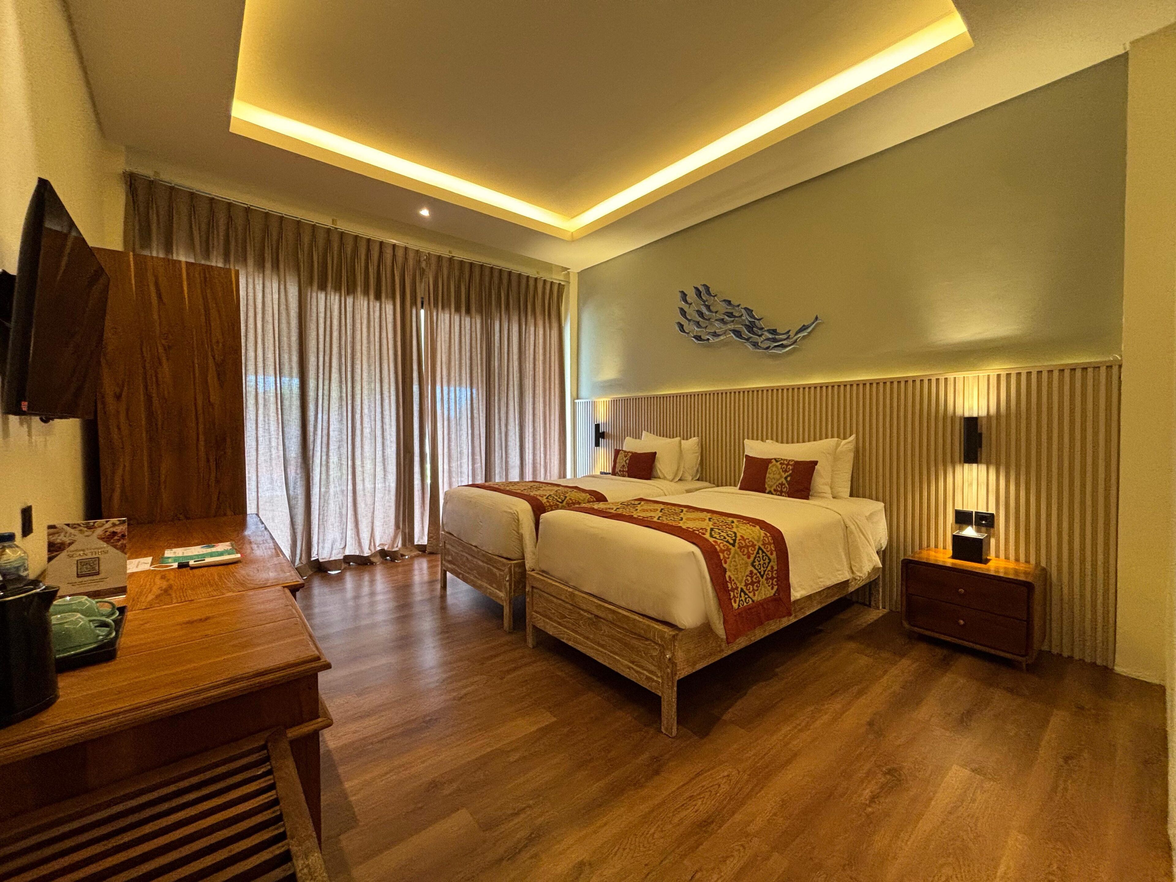 A hotel room with a large bed, bedside tables, a desk, and a wall-mounted TV.