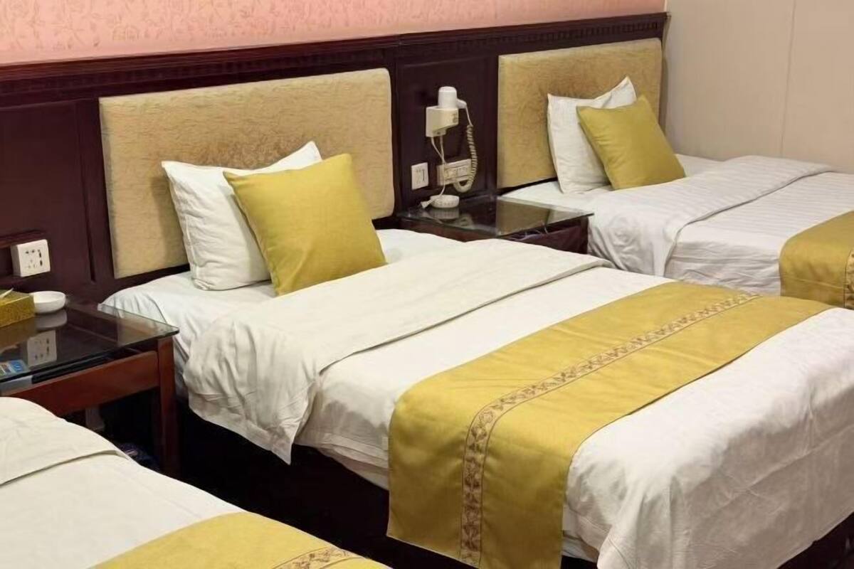 Une chambre d’hôtel avec deux lits, chacun doté d’une tête de lit, d’une table de chevet et d’un téléphone.