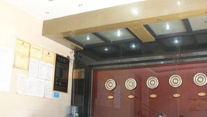 A reception area with a counter, certificates on the wall, and a decorative wall panel. - Jixuan Hotel (Zhongshan)