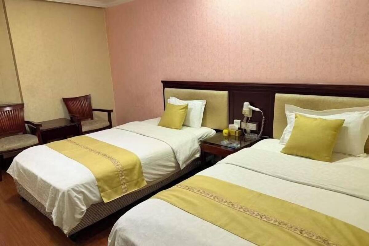 Une chambre d’hôtel avec deux lits, une chaise, une table de chevet et un téléphone.