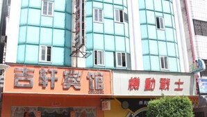 A building with a teal facade and orange signage for a hotel and a massage service. - Jixuan Hotel (Zhongshan)