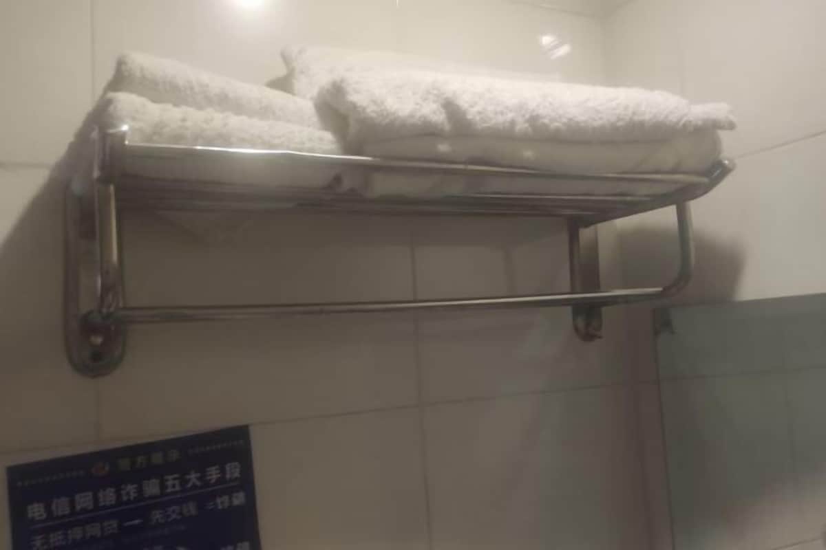Un porte-serviettes en métal, avec des serviettes pliées, adossé à un mur carrelé.