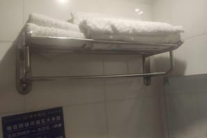 Un porte-serviettes en métal, avec des serviettes pliées, adossé à un mur carrelé.