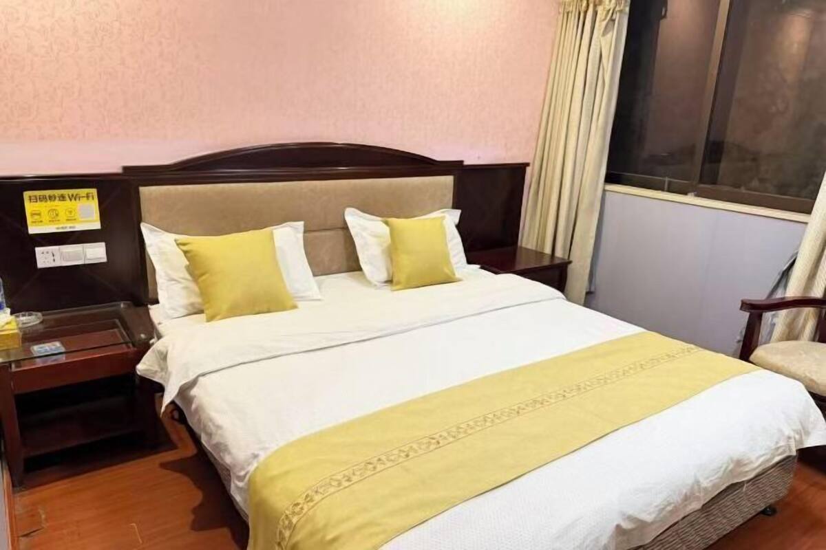 Une chambre d’hôtel avec un lit, une table de chevet, une chaise et une fenêtre.