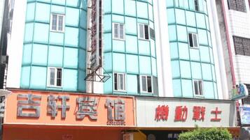 A building with a teal facade and multiple windows. There are signs for a hotel and a restaurant on the ground floor.