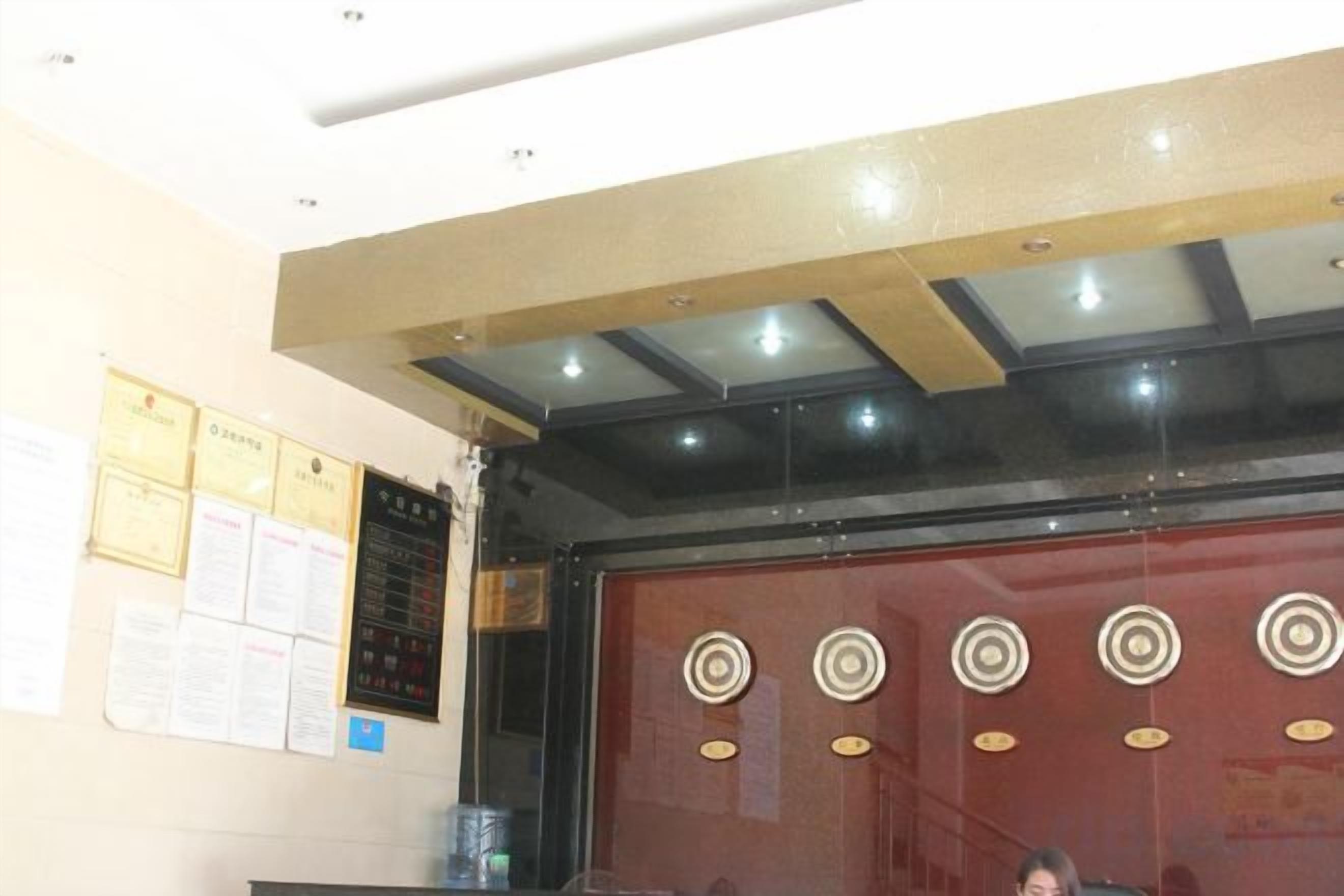 A reception area with a counter, a wall with certificates, and a ceiling with recessed lighting.