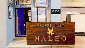 Un comptoir d’accueil avec une pancarte indiquant « RÉCEPTION MALEO » et un logo représentant un oiseau doré.