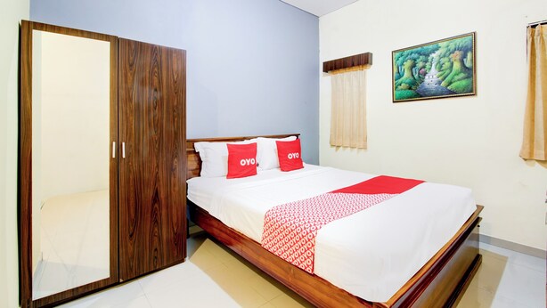 Une chambre à coucher avec un lit en bois, du linge de lit blanc et une couverture à motifs rouges et blancs.