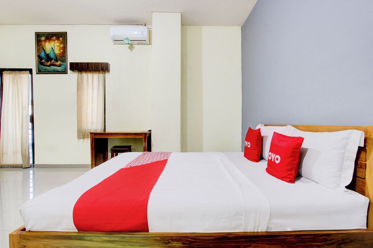 A neatly made bed with a red and white bedspread, two red pillows with the word "YOYO" on them, and a wooden headboard.