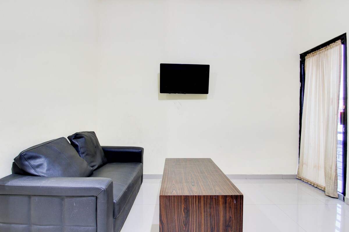 A modern living room with a grey sofa, a wooden coffee table, and a flat-screen TV mounted on the wall.