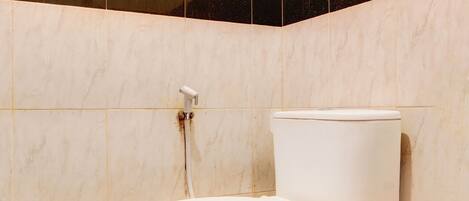 A bathroom with a toilet, a handrail, and tiled walls.