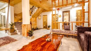 A spacious living area with a wooden ceiling, a large wooden coffee table, and a sofa. - Amber Cottage Manali (Manali)