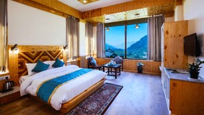 A wooden-paneled room with a bed, a desk, and a TV. - Amber Cottage Manali (Manali)