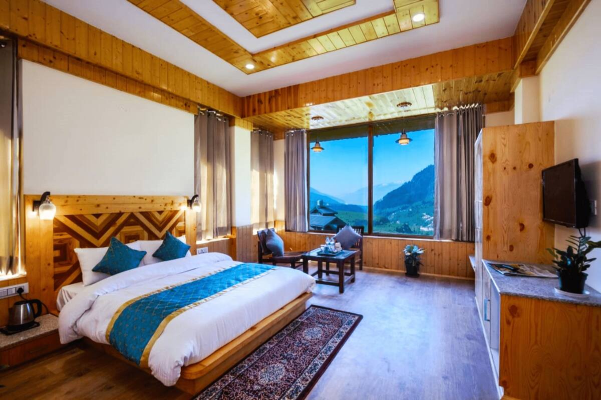 A wooden-paneled room with a bed, a desk, and a TV.