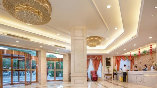 A spacious lobby with a reception desk, a large pillar, and a chandelier. - Vienna Hotel (Dunhuang)