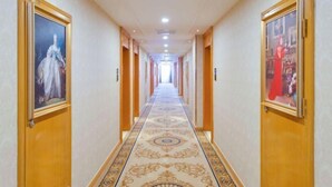 A long hallway with a patterned carpet, wooden doors, and framed artwork on the walls. - Vienna Hotel (Dunhuang)