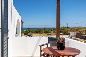 A balcony with a view of the sea, a wooden table, and a chair.