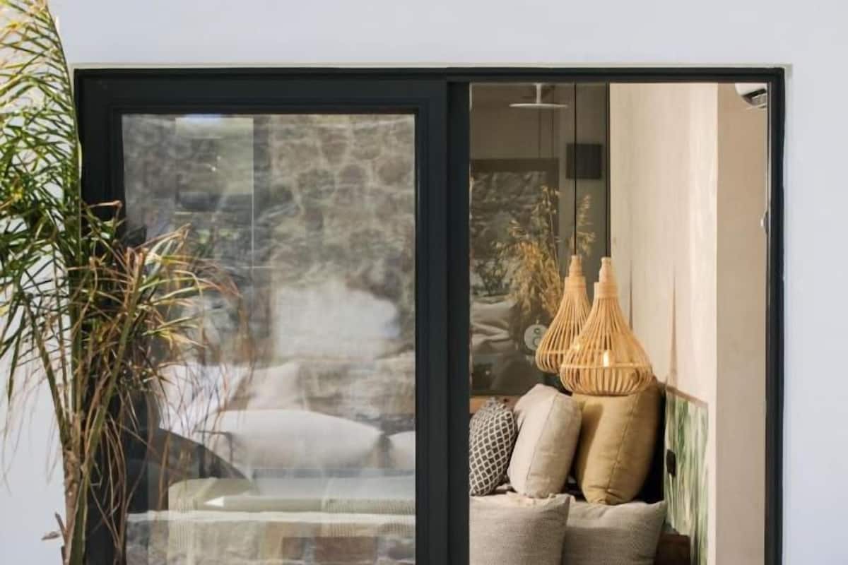 A modern outdoor seating area with a glass door leading to a stone interior.