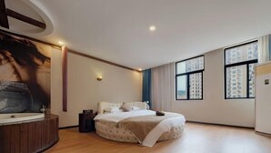 Un dormitorio moderno con una cama grande, una bañera integrada y amplias ventanas con vista a la ciudad.