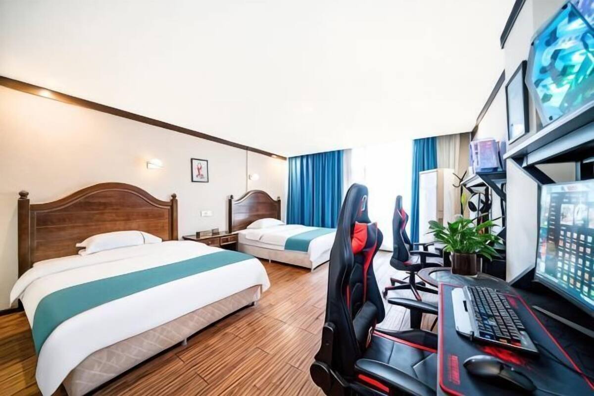 A hotel room with two beds, a desk with a computer, and a chair.