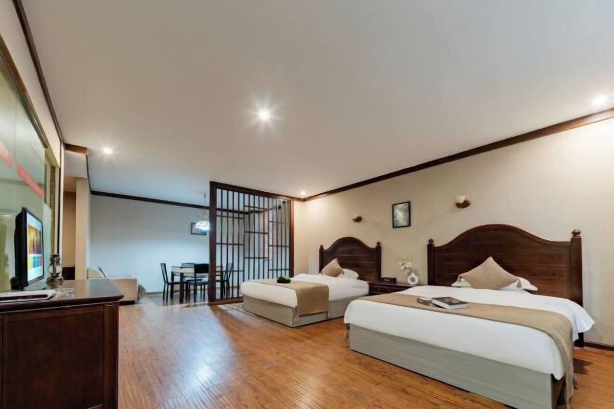 A hotel room with two beds, a desk, and a TV.